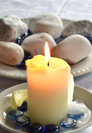 A candle with small stones on a plate
