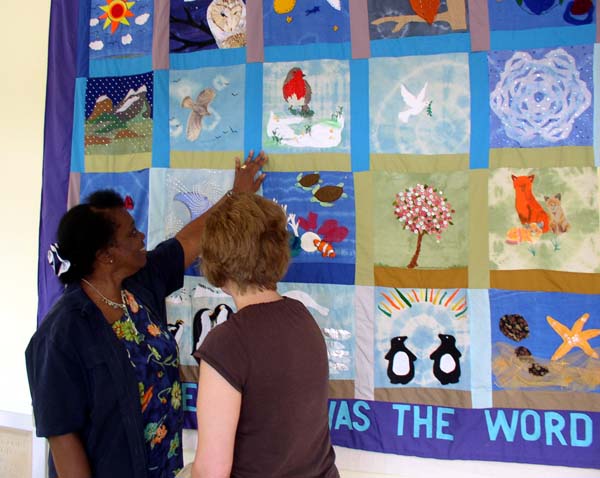 Two church members pointing out scenes in the tapestry