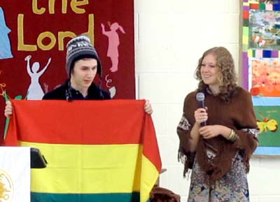 Two teenagers at the front of the church, one holding a Bolivian flag