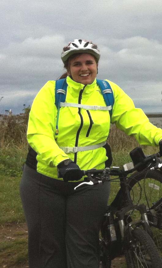 Miriam stands holding her bike
