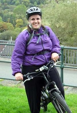 Miriam stands holding her bike