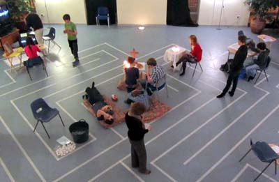 Young people standing, sitting and kneeling at various points around the hall
