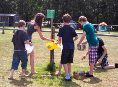 Young people collecting water from a tap in a field