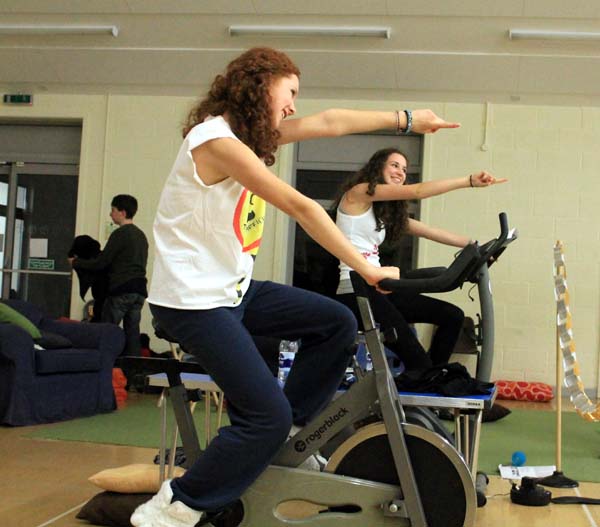 Both cyclists extend their arms as part of a dance