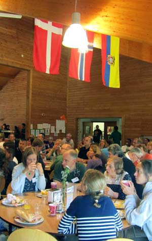 People sitting round a table in a dining hall with flags hanging from the ceiling